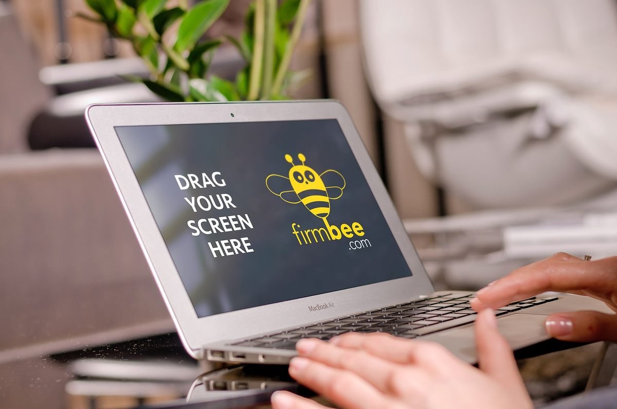 Une main tapote le clavier d'un ordinateur portable affichant un logo d'abeille