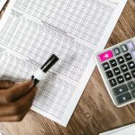 Une main écrit sur un tableau de chiffres avec une calculatrice