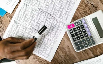 Une main écrit sur un tableau de chiffres avec une calculatrice