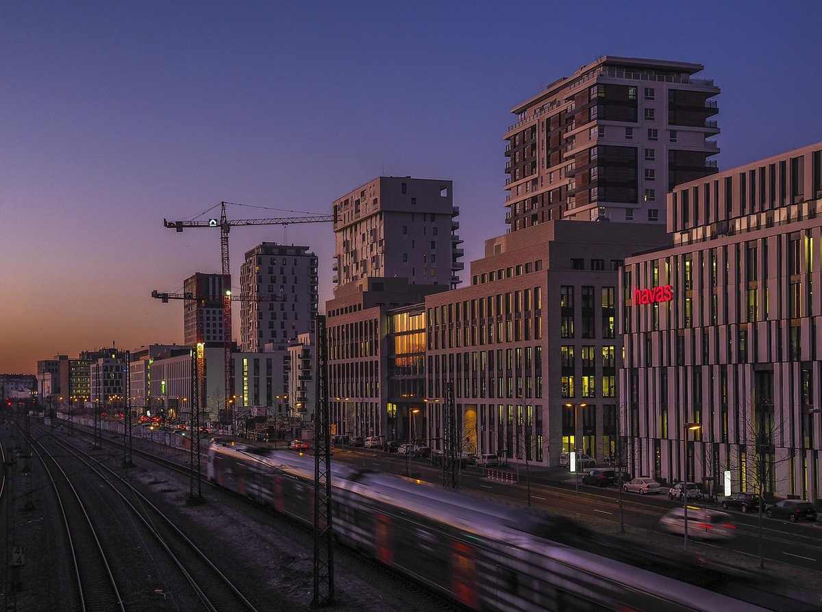 Vue d'une ville au crépuscule avec un train sur les voies et des bâtiments en construction