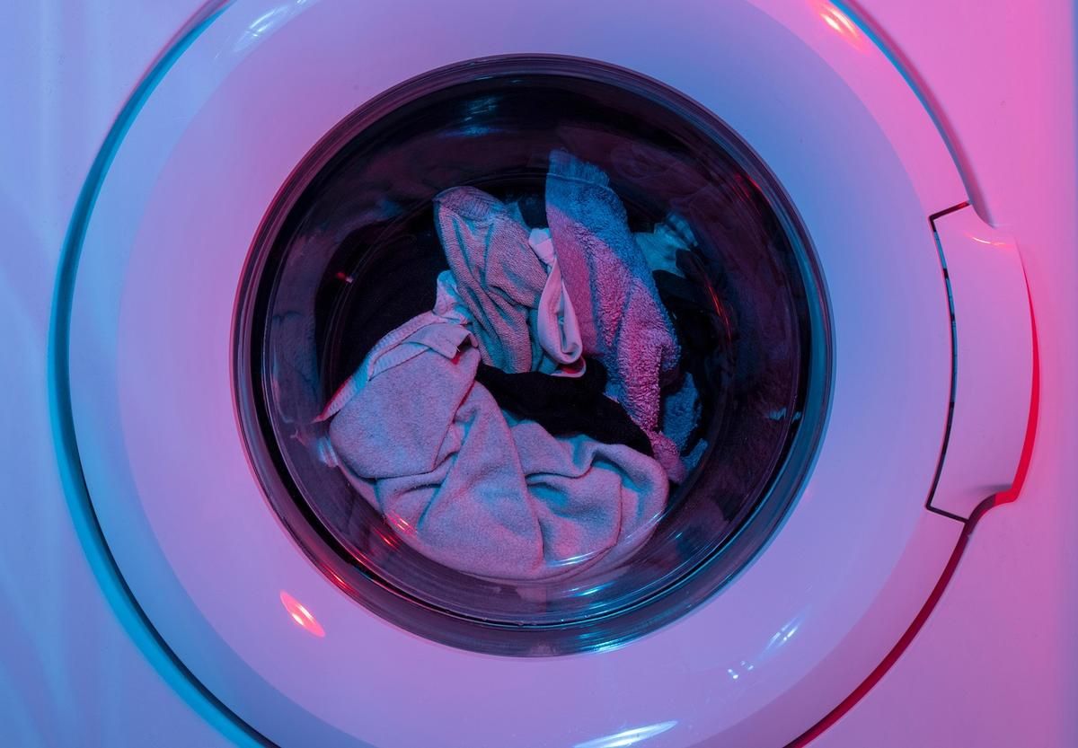 Machine à laver avec vêtements à l'intérieur, lumière colorée