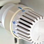 Un thermostat mural avec une main qui tourne le cadran pour régler la température