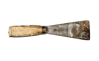 Un couteau à enduire usé avec manche en bois, métallique, posé horizontalement