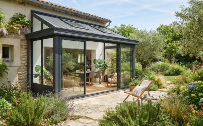 Véranda moderne en aluminium accolée à une maison, baies vitrées, jardin ensoleillé