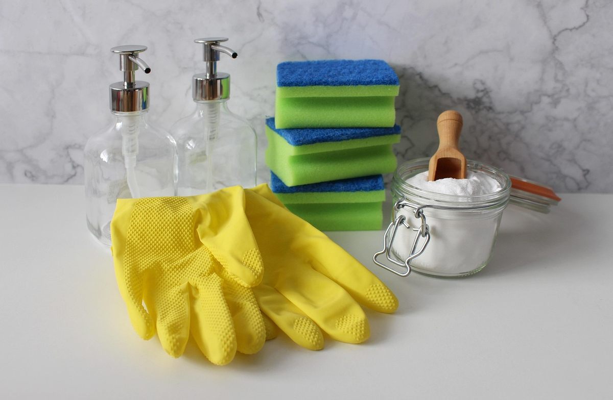 Gants jaunes, flacons de savon, éponges, pot de bicarbonate et cuillère en bois